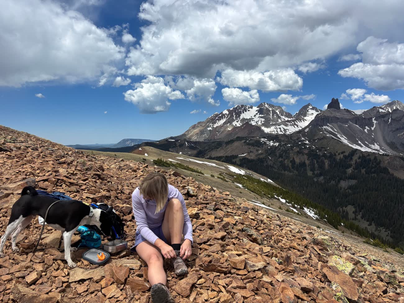 Hiker and dog resting on a high ridge in the San Juan Mountains